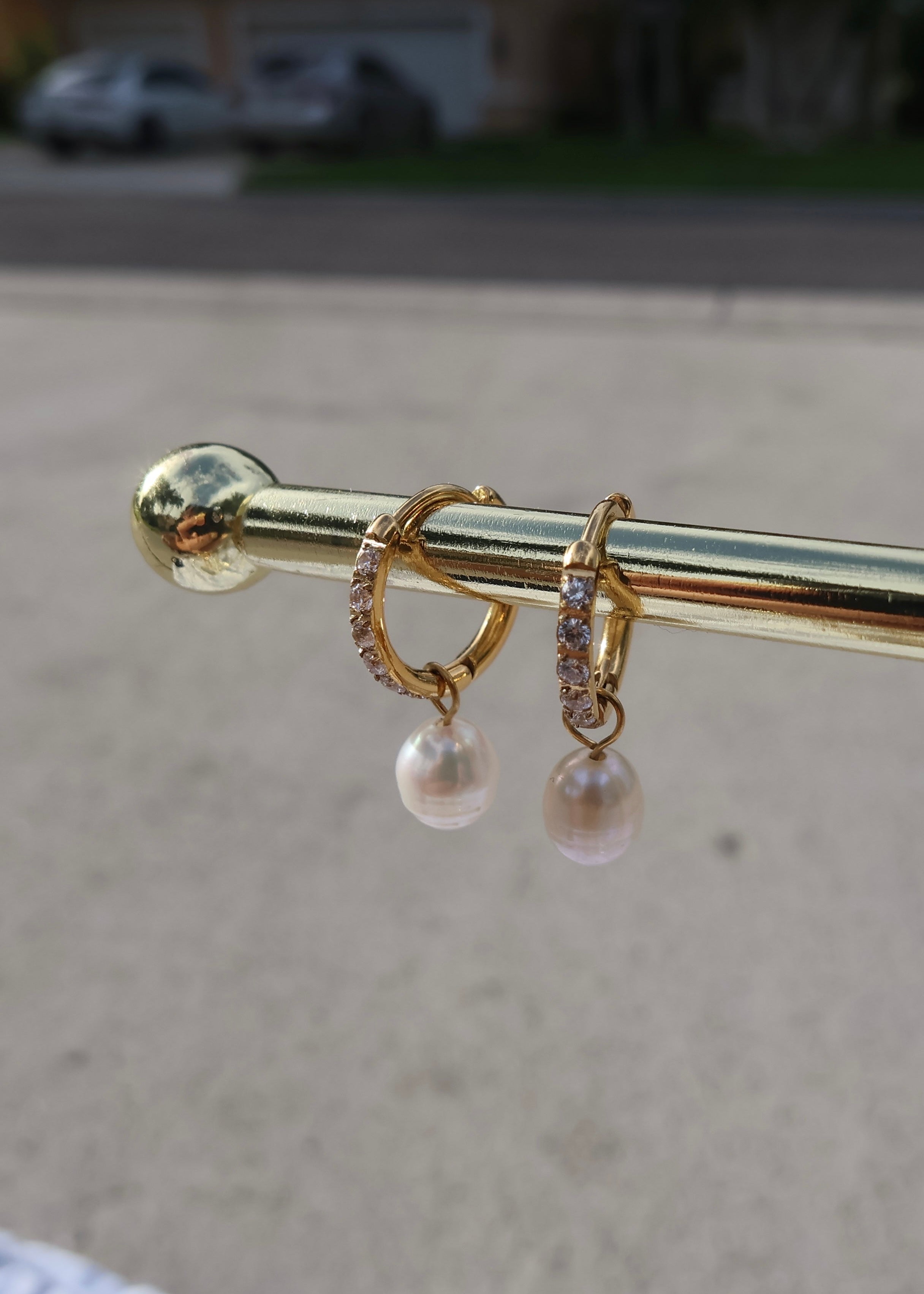 Gold earring with pearl drops on a blurred background