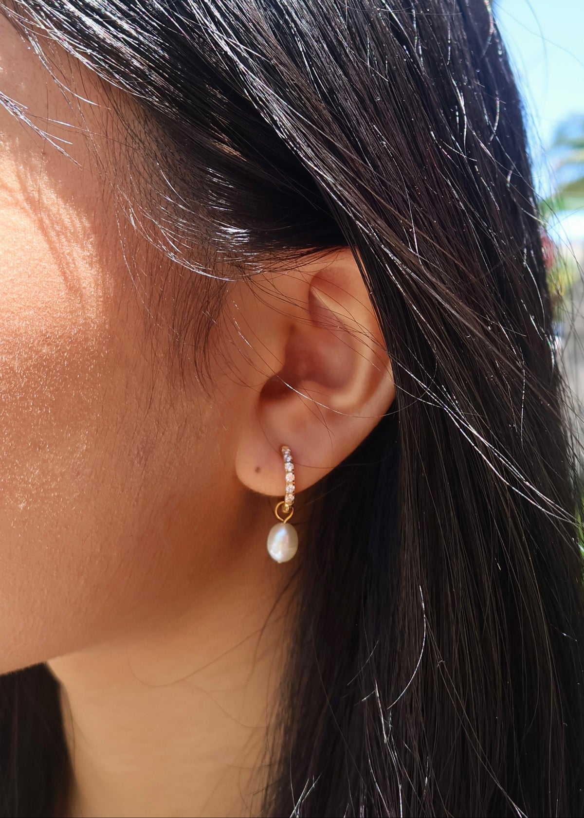 Close-up of an ear wearing a pearl earring with blurred background